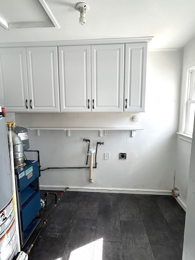 washroom featuring electric dryer hookup, baseboards, gas water heater, and cabinet space