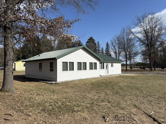 view of property exterior with a lawn and metal roof