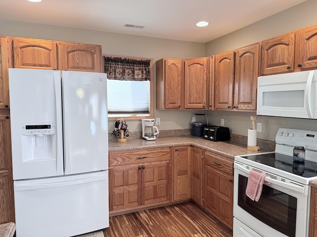 kitchen featuring white appliances, light countertops, dark wood finished floors, recessed lighting, and visible vents