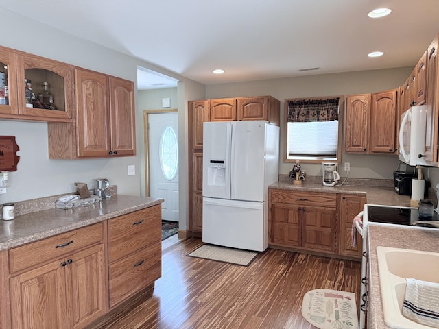 kitchen featuring glass insert cabinets, light countertops, white appliances, and dark wood-type flooring