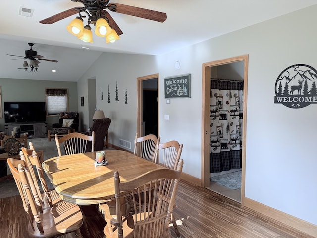 dining area with ceiling fan, baseboards, wood finished floors, lofted ceiling, and visible vents