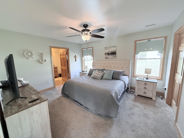 carpeted bedroom with baseboards, ceiling fan, ensuite bath, and visible vents