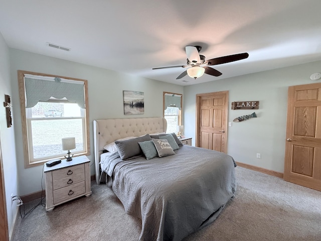 carpeted bedroom with visible vents, a ceiling fan, baseboards, and multiple windows