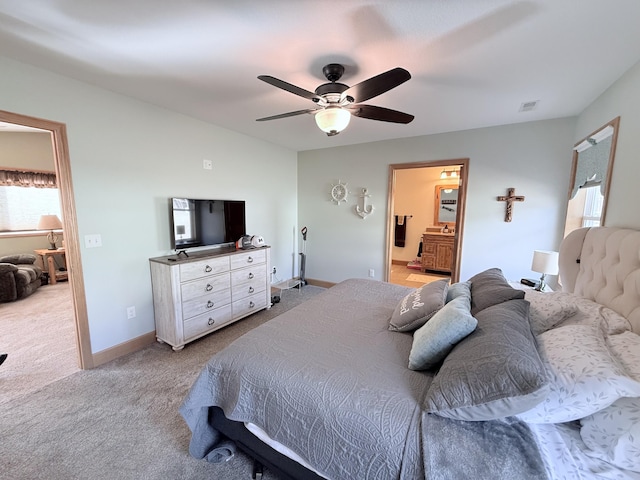 bedroom featuring ceiling fan, light colored carpet, visible vents, baseboards, and connected bathroom