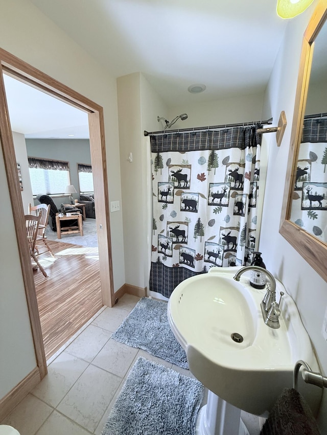 bathroom with a shower with curtain, a sink, and baseboards