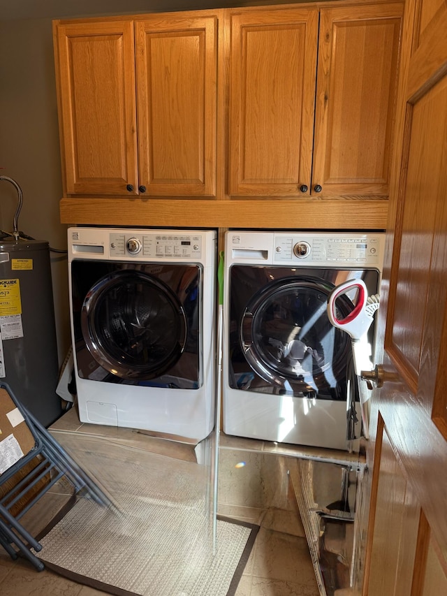washroom with water heater, cabinet space, and washer and dryer