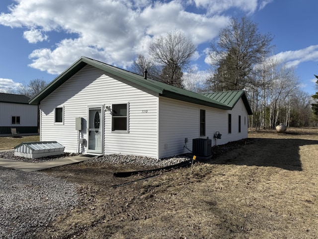 rear view of property with central AC unit and metal roof