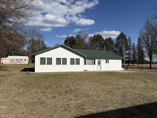 back of property with a yard and metal roof