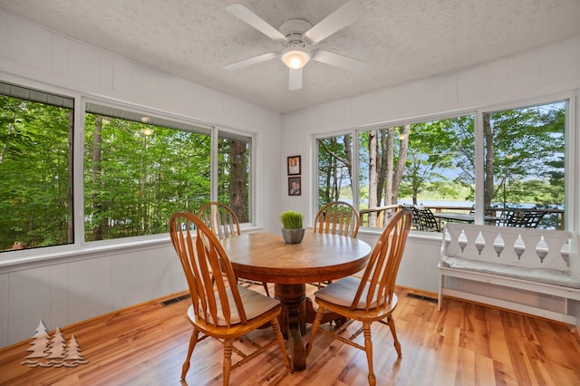 dining space with visible vents, light wood-type flooring, a textured ceiling, and ceiling fan
