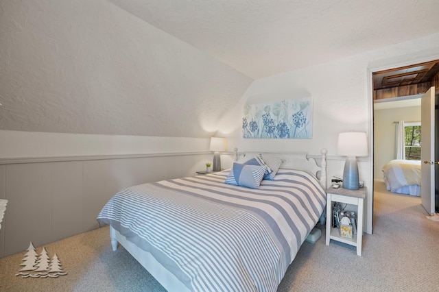 carpeted bedroom with a decorative wall and lofted ceiling