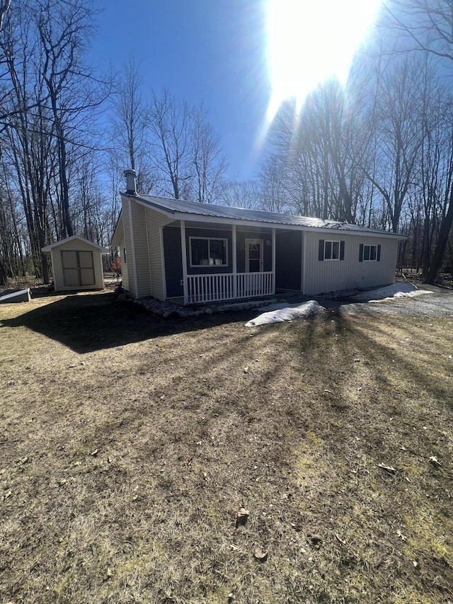 view of front of house featuring a porch, a storage shed, and an outdoor structure