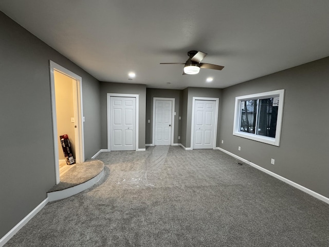 unfurnished bedroom with two closets, baseboards, a ceiling fan, and carpet