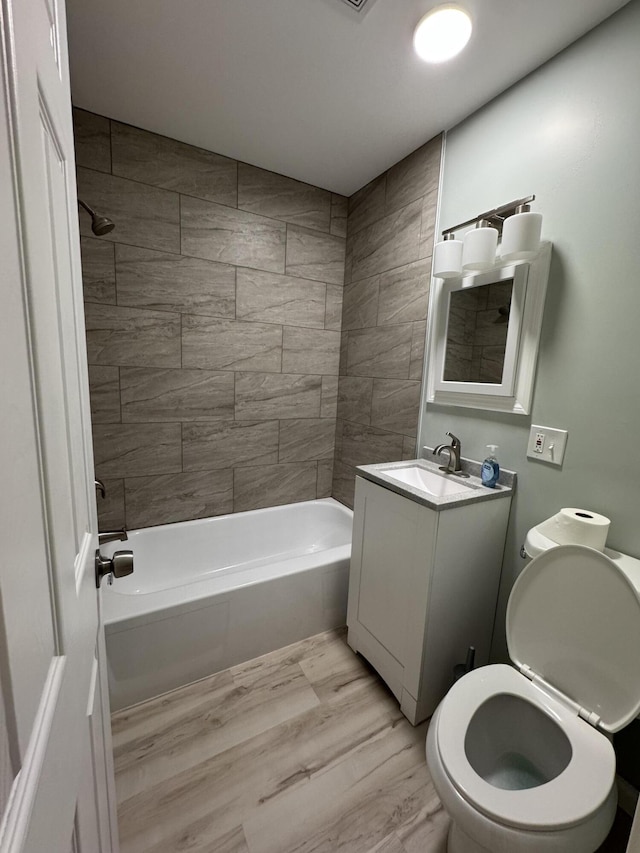 full bath with toilet, bathing tub / shower combination, wood finished floors, and vanity