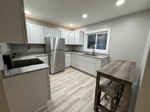 kitchen featuring a sink, freestanding refrigerator, recessed lighting, and stove