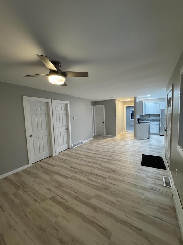 unfurnished living room featuring visible vents, a ceiling fan, and light wood-style floors