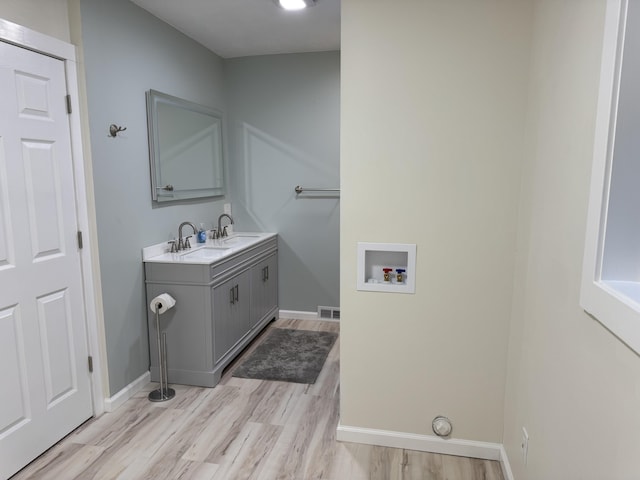 laundry area featuring baseboards, washer hookup, light wood-style floors, visible vents, and cabinet space