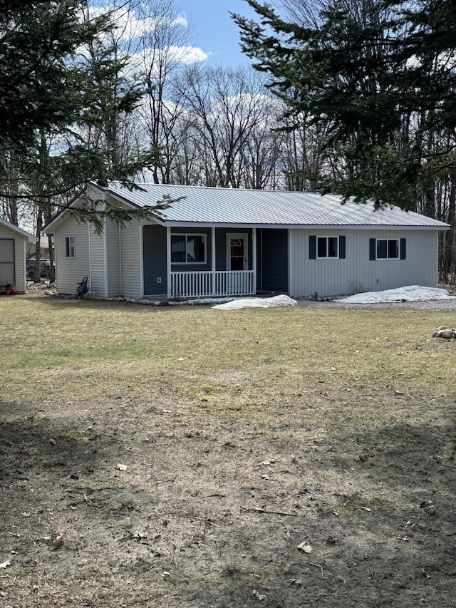 ranch-style home featuring metal roof, a front lawn, and covered porch