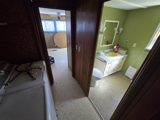 2051 Stutesman Dr, Fairview, MI 48621 - bathroom featuring vanity, tile patterned floors, toilet, wood walls, and washer / dryer