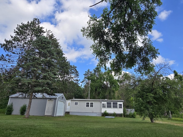 2051 Stutesman Dr, Fairview, MI 48621 - view of front of home with a front lawn, a detached garage, and an outdoor structure