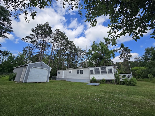 2051 Stutesman Dr, Fairview, MI 48621 - rear view of house featuring a detached garage, a yard, and an outbuilding