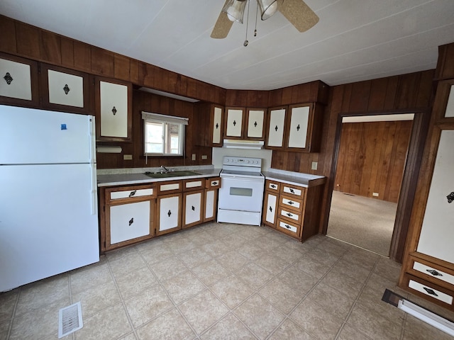 2051 Stutesman Dr, Fairview, MI 48621 - kitchen with white appliances, wood walls, light countertops, ceiling fan, and under cabinet range hood