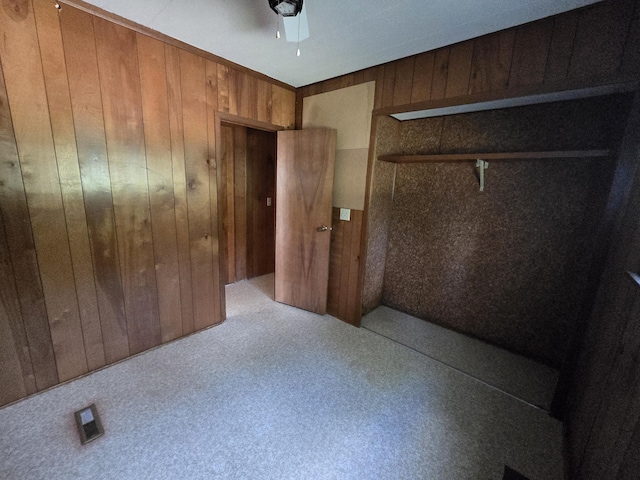 2051 Stutesman Dr, Fairview, MI 48621 - unfurnished bedroom with wooden walls, carpet flooring, a closet, and ceiling fan