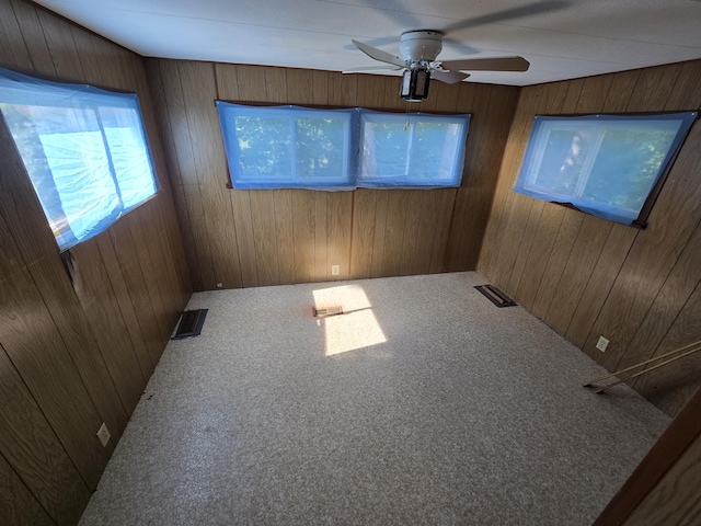 2051 Stutesman Dr, Fairview, MI 48621 - carpeted empty room featuring wooden walls and ceiling fan