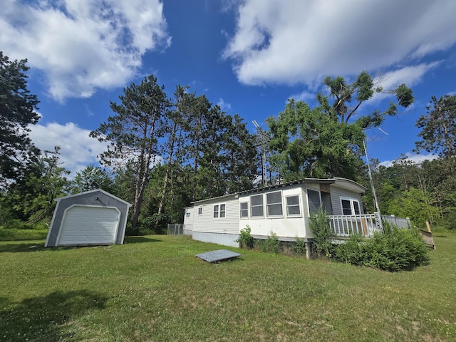 2051 Stutesman Dr, Fairview, MI 48621 - back of property featuring a garage, an outdoor structure, a lawn, and a wooden deck