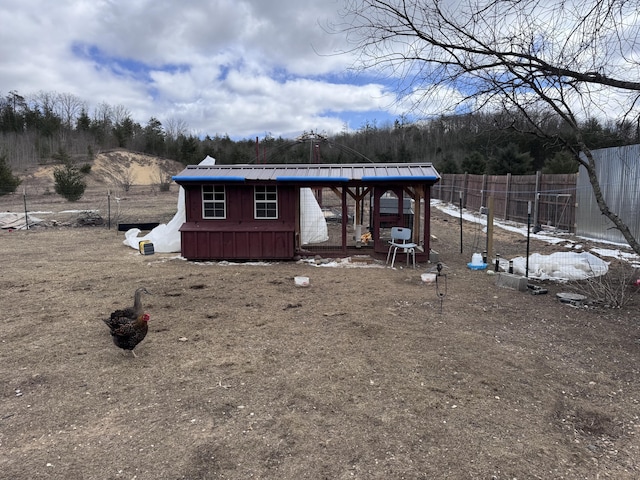 back of property with exterior structure, fence, an outbuilding, and metal roof