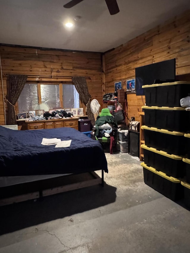 bedroom featuring unfinished concrete floors, wood walls, and a ceiling fan