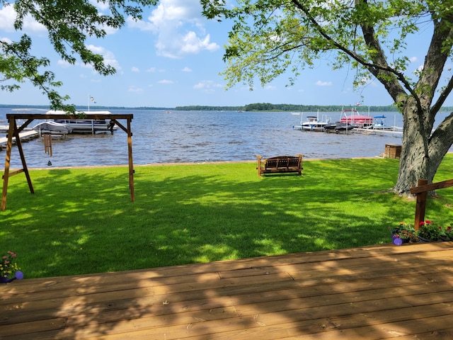 view of dock featuring a water view, a lawn, and boat lift