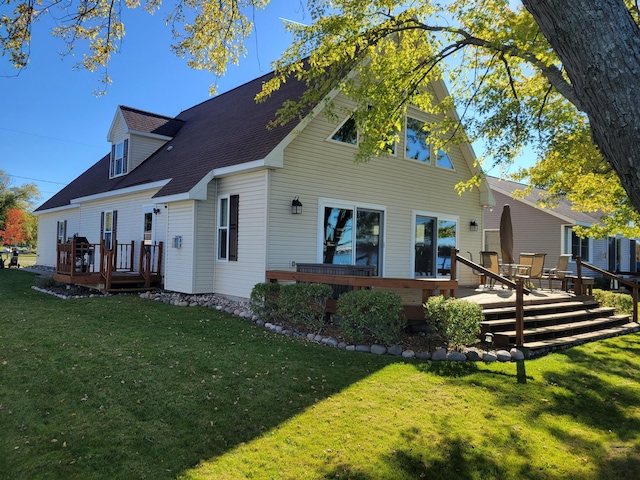 back of house with a shingled roof, a wooden deck, and a lawn