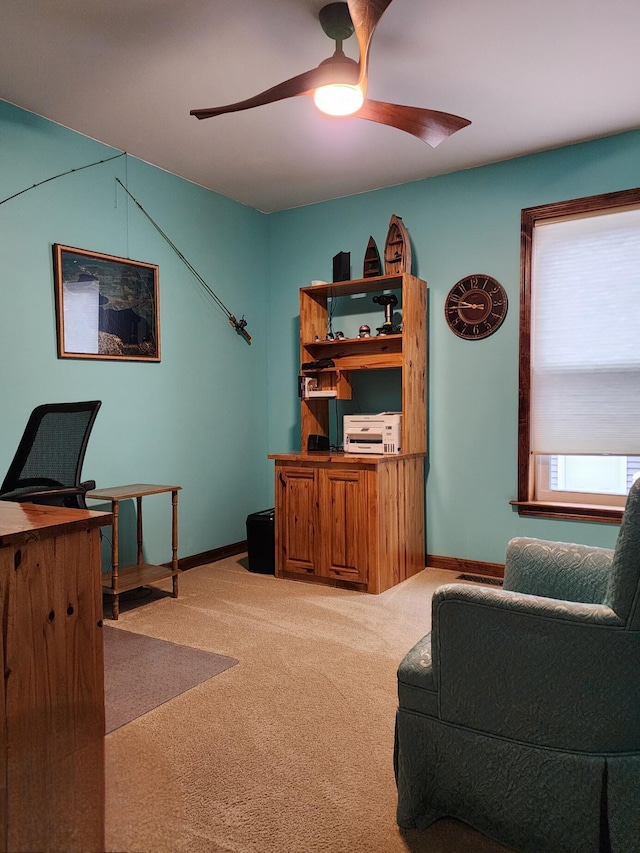 carpeted office with baseboards and a ceiling fan