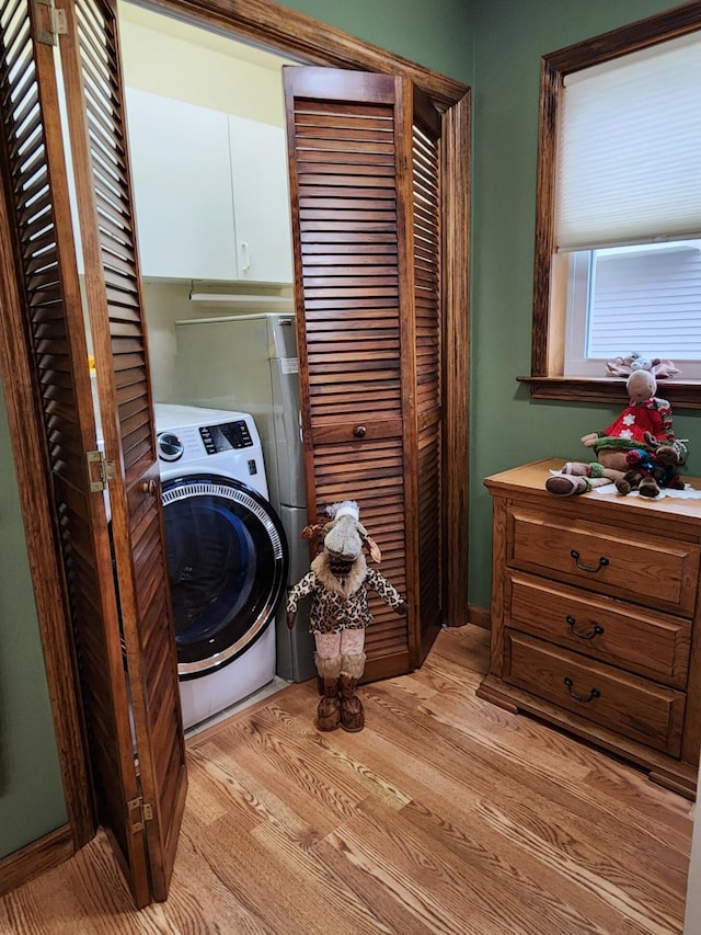 laundry room featuring cabinet space, washer / clothes dryer, and light wood-style flooring