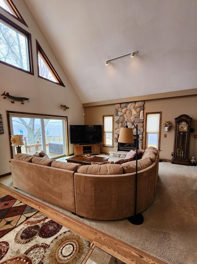 living area with light colored carpet, high vaulted ceiling, baseboards, and a wealth of natural light