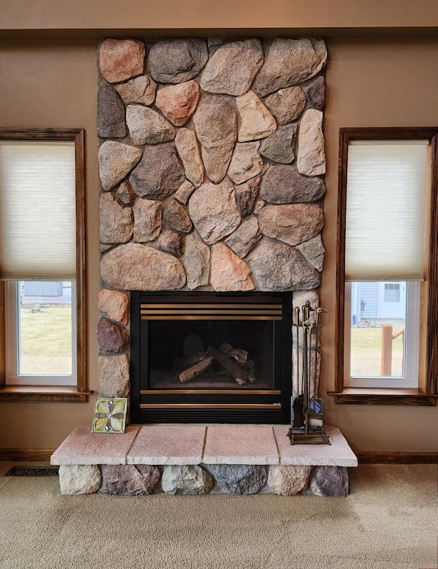 room details with carpet flooring, visible vents, a stone fireplace, and baseboards