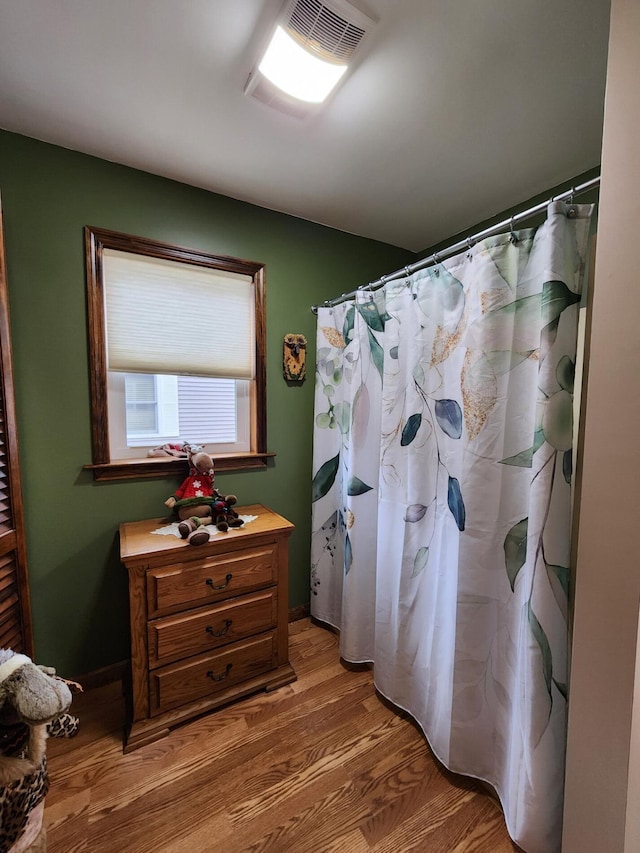 full bath featuring curtained shower and wood finished floors