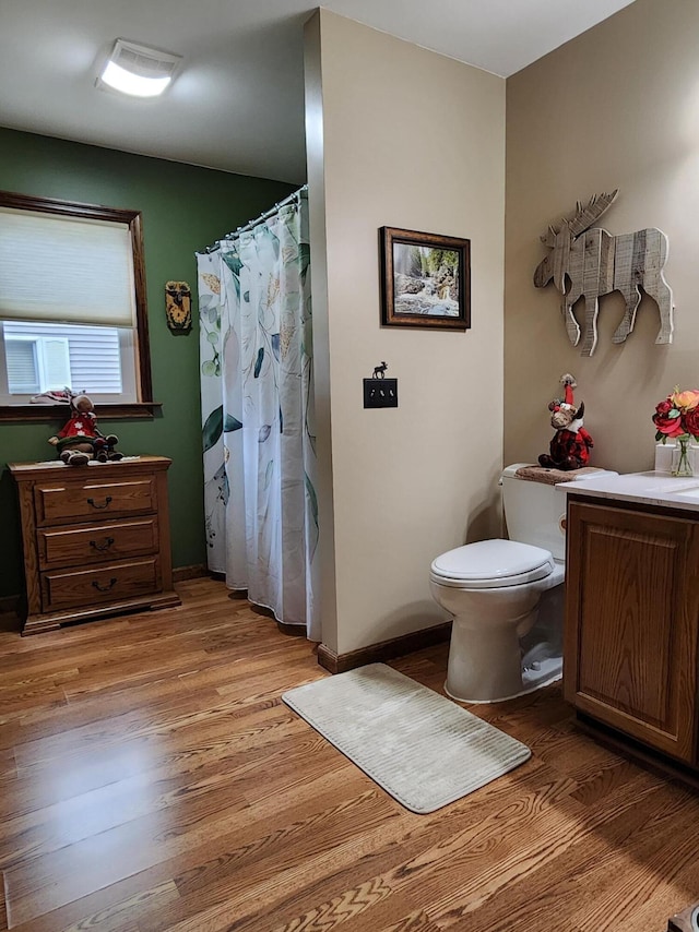 bathroom with vanity, a shower with curtain, toilet, and wood finished floors