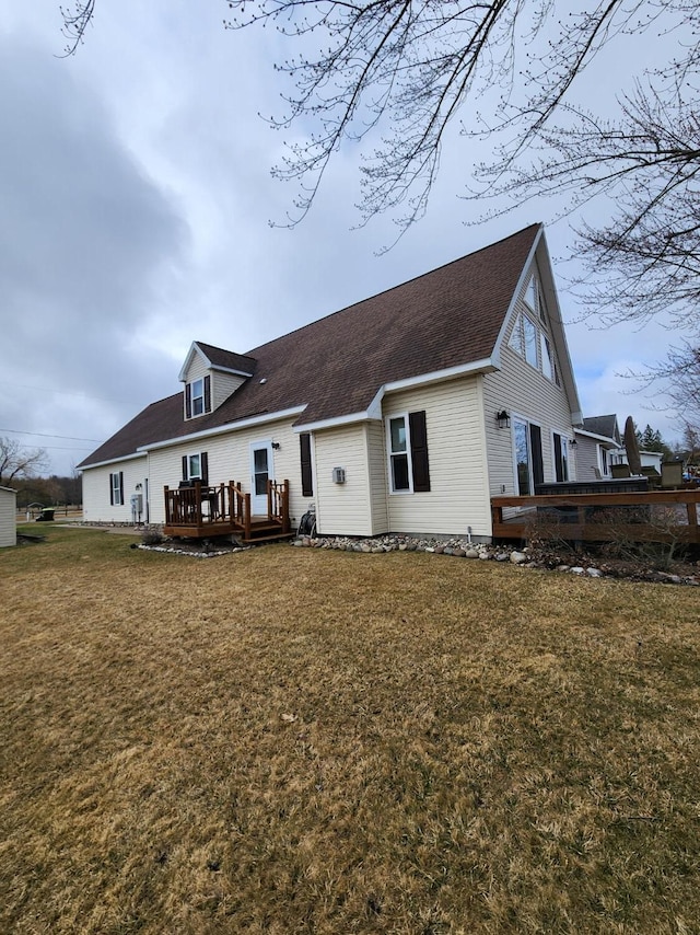 view of front of property featuring a front yard, a wooden deck, and roof with shingles