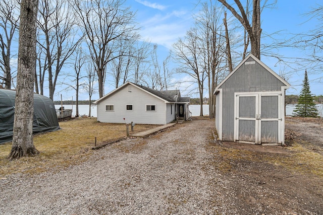 4640 Hiawatha Dr, Cheboygan, MI 49721 - view of side of property featuring an outdoor structure, a water view, a shed, and gravel driveway