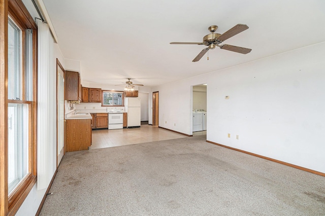 4640 Hiawatha Dr, Cheboygan, MI 49721 - unfurnished living room featuring baseboards, ceiling fan, washer and dryer, and light carpet