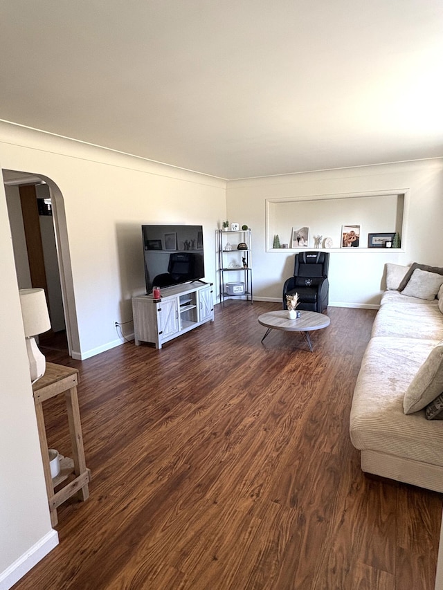 living room with arched walkways, baseboards, and wood finished floors