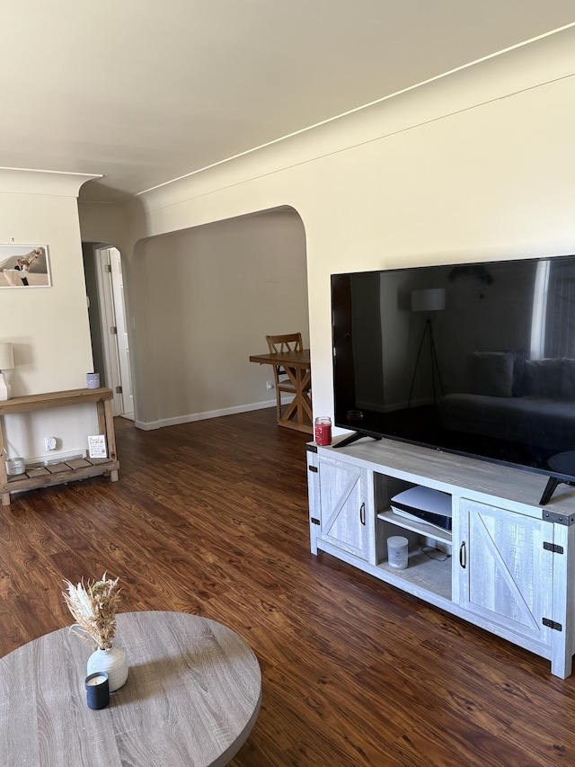 living room with baseboards, arched walkways, and wood finished floors