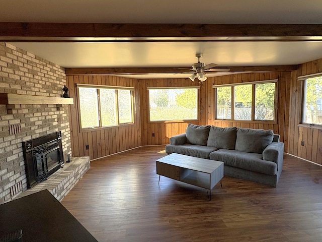 living room with a fireplace, beamed ceiling, and wooden walls