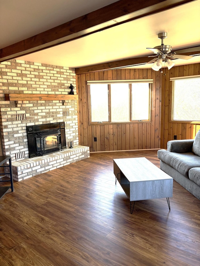 living room featuring wooden walls, ceiling fan, beam ceiling, and wood finished floors