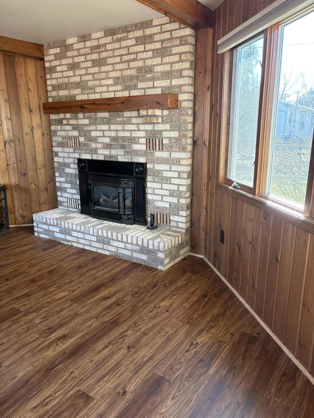 unfurnished living room with a brick fireplace, wood walls, wood finished floors, and a wealth of natural light
