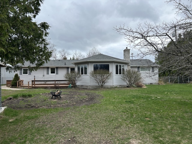 2141 S First Ave, Alpena, MI 49707 - view of front facade with a wooden deck, a chimney, a front lawn, and an outdoor fire pit