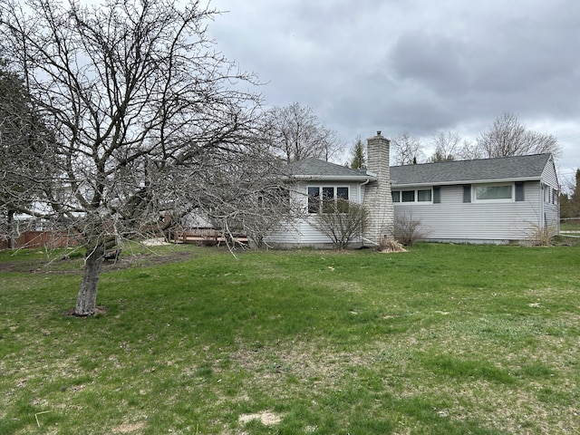 2141 S First Ave, Alpena, MI 49707 - view of front of house featuring a chimney, a shingled roof, and a front lawn