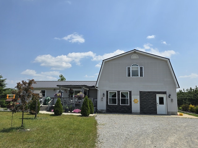 1300 N Perry Creek Rd, Fairview, MI 48621 - colonial inspired home with a gambrel roof, a front yard, and stone siding
