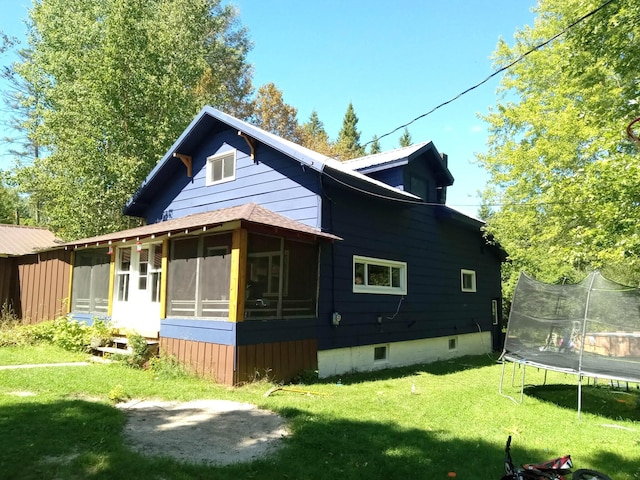 3468 W Nye Rd, Hessel, MI 49745 - view of property exterior featuring a sunroom, a trampoline, a yard, and a shingled roof